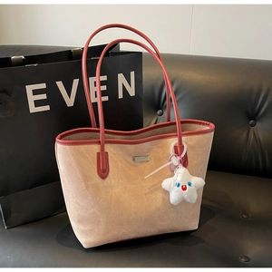 Détail du sac cabas en daim kaki clair avec anses en cuir rouge et breloque étoile en peluche