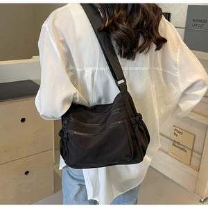 Model wearing a large capacity black nylon crossbody bag with multi-zipper pockets