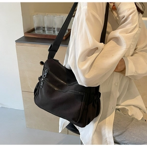 Detail of black nylon crossbody bag featuring double front zippers and side pocket