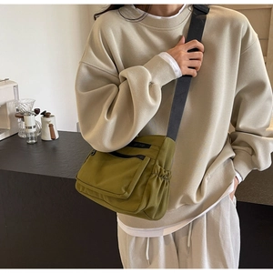 Detailed view of an olive green nylon crossbody bag with side drawstring and wide strap