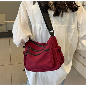 Burgundy nylon crossbody bag featuring multiple zipper pockets and adjustable wide strap