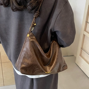 Dark coffee crescent tote bag with knot detail and gold hardware in a 45-degree side view
