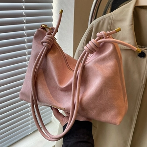 Soft pink faux leather tote bag with knotted shoulder strap and pebbled texture