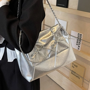 Sac fourre-tout argenté avec détail nœud et bandoulière chaîne porté à l'épaule