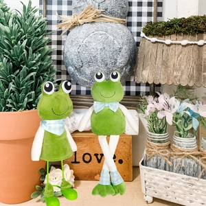 Close-up of cute green long-legged frog plush dolls in a cozy rustic garden setting