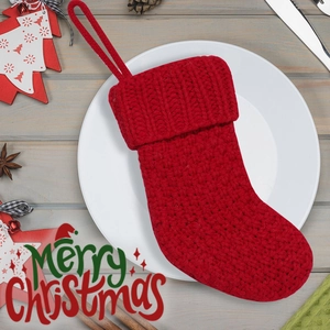 Detail of red cable-knit Christmas stocking with festive pine cones and table decor