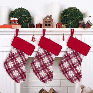 Three red checkered Christmas stockings hanging on a white fireplace mantle decoration