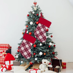 Detail of red and white plaid Christmas stockings with hanging loops on a festive tree