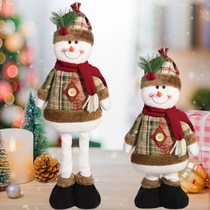 Close-up of plush Christmas snowmen with plaid hats and red scarves in warm festive light