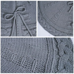 Gray knitted Christmas tree skirt with cable knit patterns and a decorative bow tie