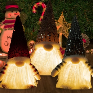 Close-up of three glowing Christmas gnomes with sequined hats and warm LED light beards