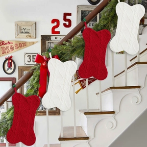 Knitted bone-shaped Christmas stockings in red and white hanging on a festive staircase
