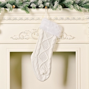 Close-up of white cable knit Christmas stocking with faux fur cuff hanging on fireplace