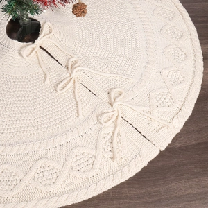 Detailed cable knit pattern on white Christmas tree skirt over dark wood floor
