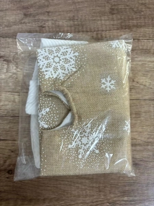 Close-up of linen Christmas tree skirt with white snowflake patterns and plush white trim