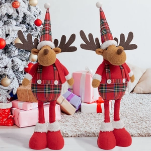 Detail of plush Christmas reindeer dolls in plaid outfits next to a snowy tree decoration