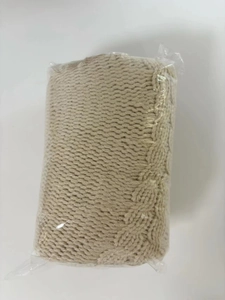 Macro detail of beige cable knit tree skirt in clear protective storage packaging