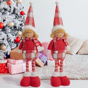 Detailed view of handmade Christmas boy doll figures standing by a festive tree with gifts