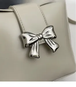 Détail d'un nœud en métal argenté sur un sac seau en cuir beige crème pour femme