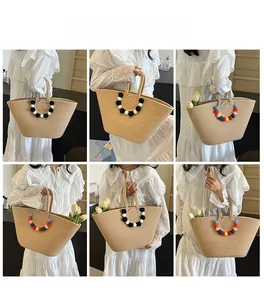 Detailed view of straw tote bag with decorative colorful pom poms and double handles