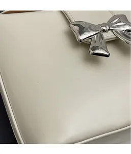 Détail du sac en cuir blanc crème avec une boucle de nœud en métal argenté poli