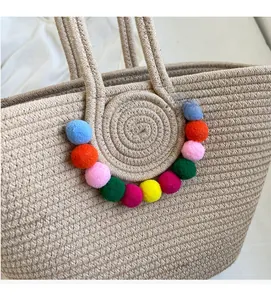 Detailed macro view of colorful pom-pom decorations on straw tote bag handle