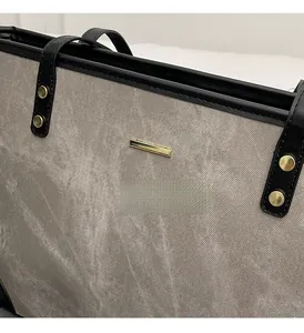 Close-up of golden hardware logo and premium textured gray fabric on a stylish tote bag