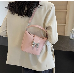 Vue arrière d'un mannequin portant un petit sac seau rose avec un nœud argenté
