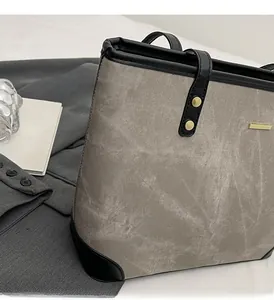 Detail of taupe canvas tote bag with black leather reinforcement and gold metallic accents