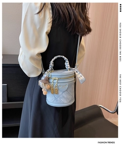 Détail du sac seau bleu clair avec texture denim et foulard en soie sur la poignée