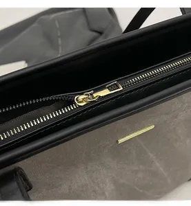 Close-up of smooth gold zipper and metallic hardware on a minimalist grey tote bag