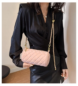 Detailed close-up of pink quilted cylinder bag with gold chain strap on a model