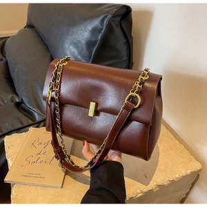 Dettaglio della borsa in pelle rosso-marrone con chiusura magnetica dorata e catena