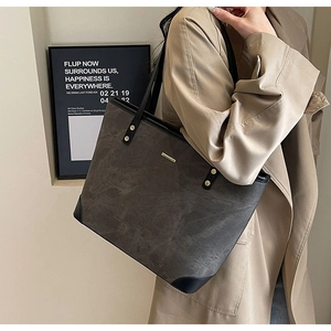 Detail of dark grey stone texture tote bag with black leather handles and gold accents