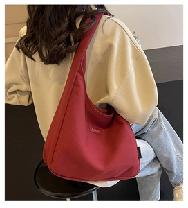Detailed view of the dark red canvas hobo bag worn by a model in a casual setting