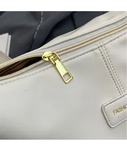Detail of white leather tote bag featuring golden zipper and FASHIO embossed leather tag