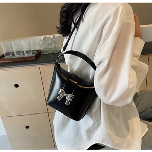 Détail du sac seau noir avec une boucle en forme de nœud argenté et une bandoulière large