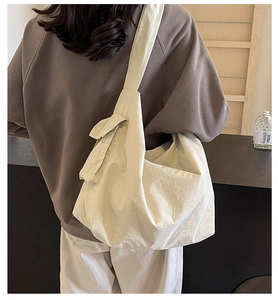 Détail du grand sac bandoulière crème montrant la texture nylon souple et la poche latérale