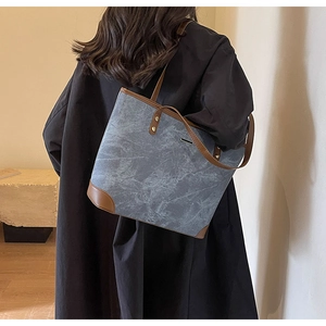 Detail of blue-grey marbled tote bag with brown leather handles worn by a model