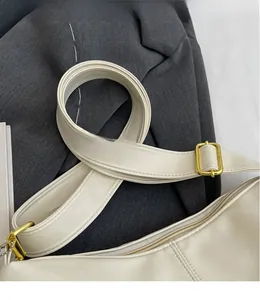 Detail of adjustable long shoulder strap with gold metal buckle on cream tote bag