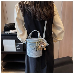 Sac cylindrique en denim bleu avec anse en foulard et pendentif porté au dos