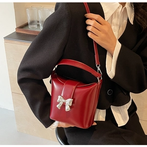 Détail du sac seau rouge avec boucle nœud argenté porté à l'épaule par un mannequin
