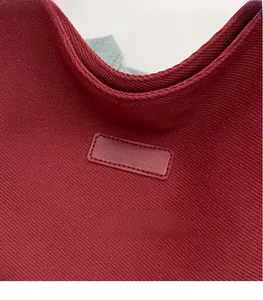Macro detail of wine red woven canvas texture and leather logo patch with gold lettering