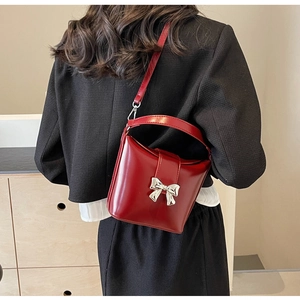 Vue d'épaule d'un sac seau rouge avec nœud argenté sur un manteau noir élégant