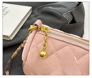 Detail showing pink quilted cylinder bag with gold zipper and smooth metal chain strap