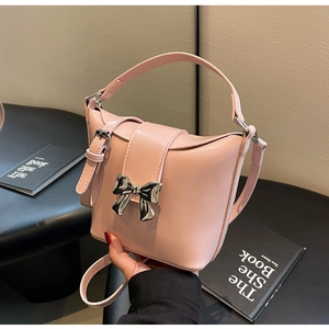 Détail du sac seau rose avec nœud en métal argenté et texture en cuir lisse élégant