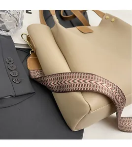 Dettaglio della borsa tote beige con ampia tracolla in tessuto colorato e ganci metallici