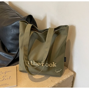 Detail of olive green canvas tote bag featuring beige embroidery and durable texture