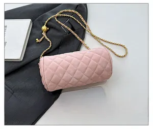 Detail of pink quilted cylinder bag featuring a gold adjustable ball chain strap