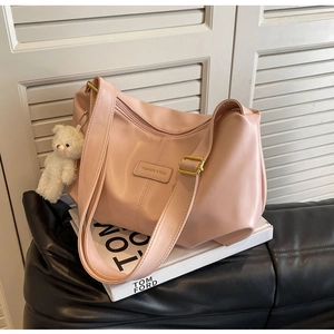 Detailed view of pink pleated hobo bag with gold hardware and white plush bear charm